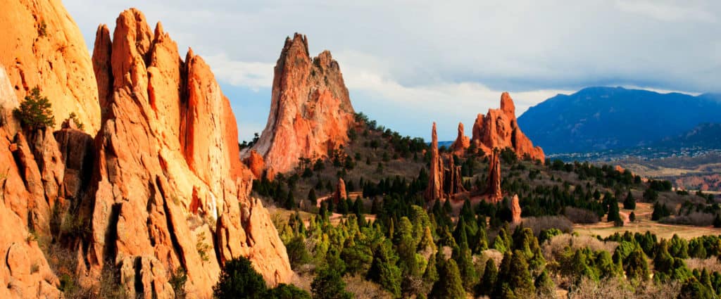 Stunning view of red rock formations and lush green trees in Colorado's scenic landscape. Perfect for real estate and outdoor adventure enthusiasts.