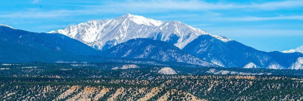 Breathtaking view of Colorado snow-capped mountains and lush green landscape, perfect for mountain homes, cabins, or investment in scenic real estate, with proximity to outdoor activities and nature.